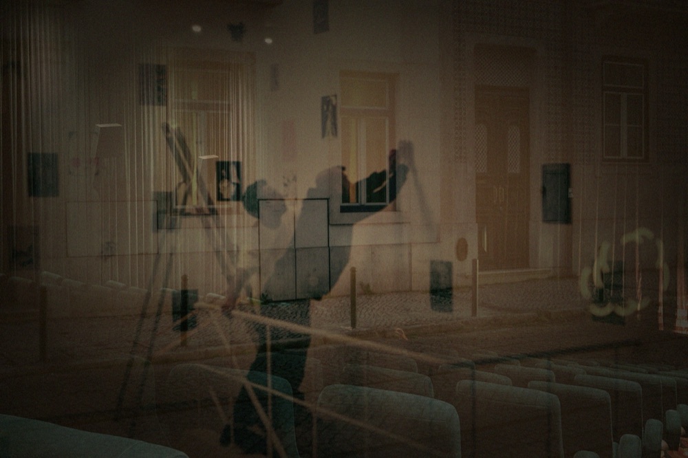 A double-exposure image blending a cultural venue interior with rows of cinema seats and artworks on the walls