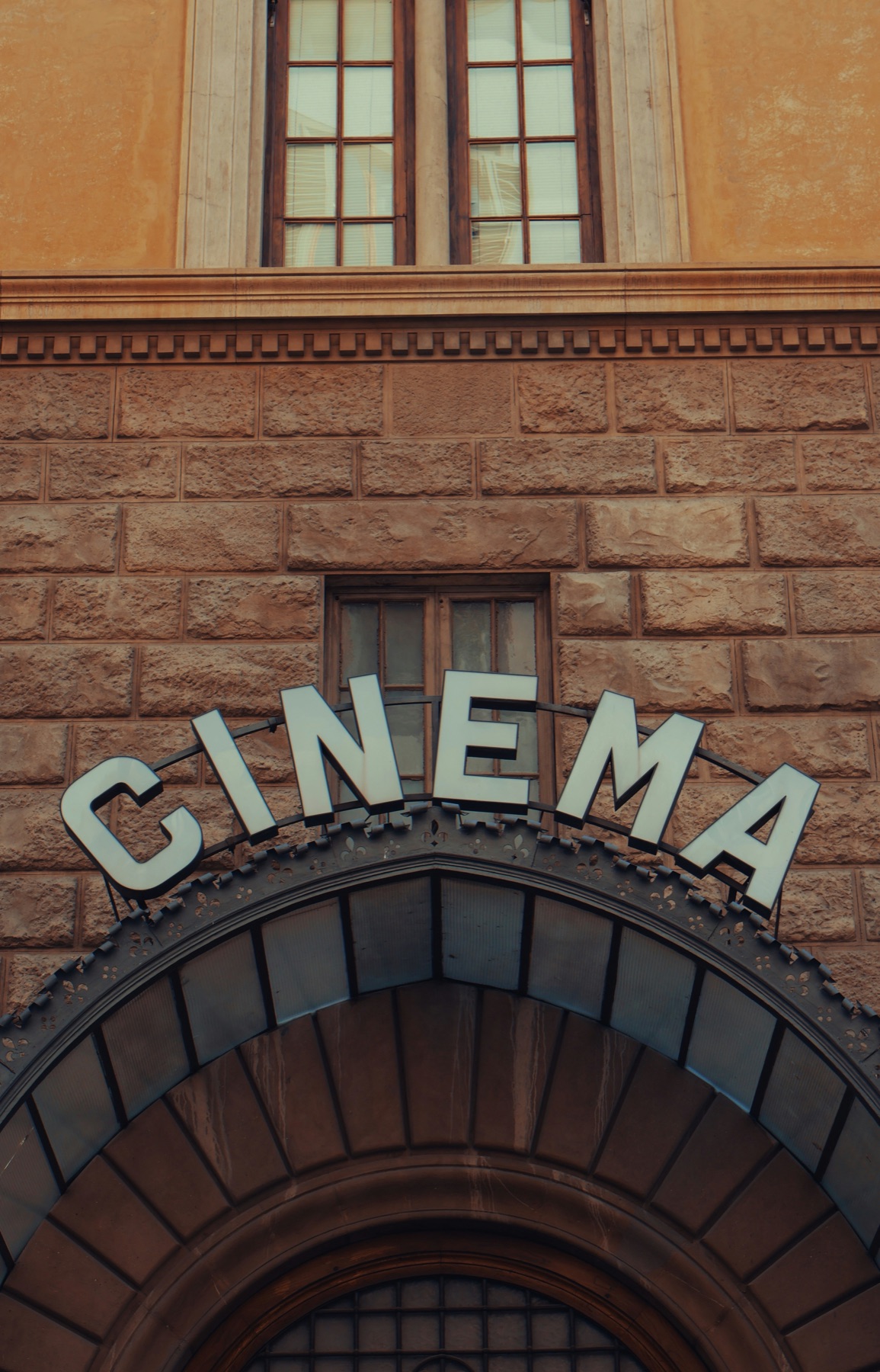 Exterior facade of a cinema building with the word Cinema in arched lettering above the entrance